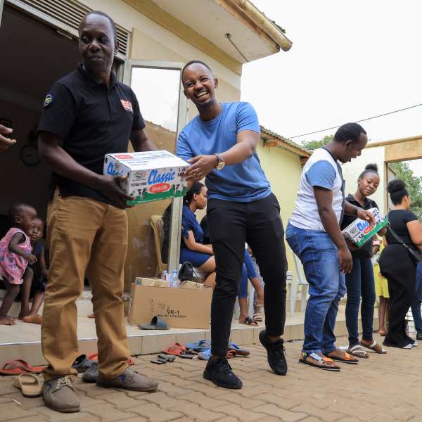 Outreach organiser, Davis Mukyenga (center) handing over some of the food stuffs donated as part of the initiative.